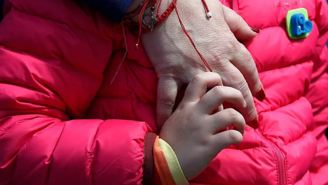 Una nena amb trastorn autista agafa la mà de la seva mare durant un acte del Dia Mundial de l'Autisme